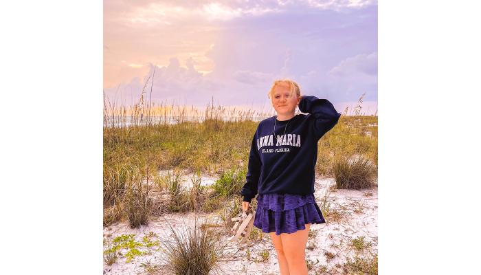 Francesca De Martino, the Sales and Marketing Intern for Felins Packaging, poses at a beach with a vibrant sunset behind her